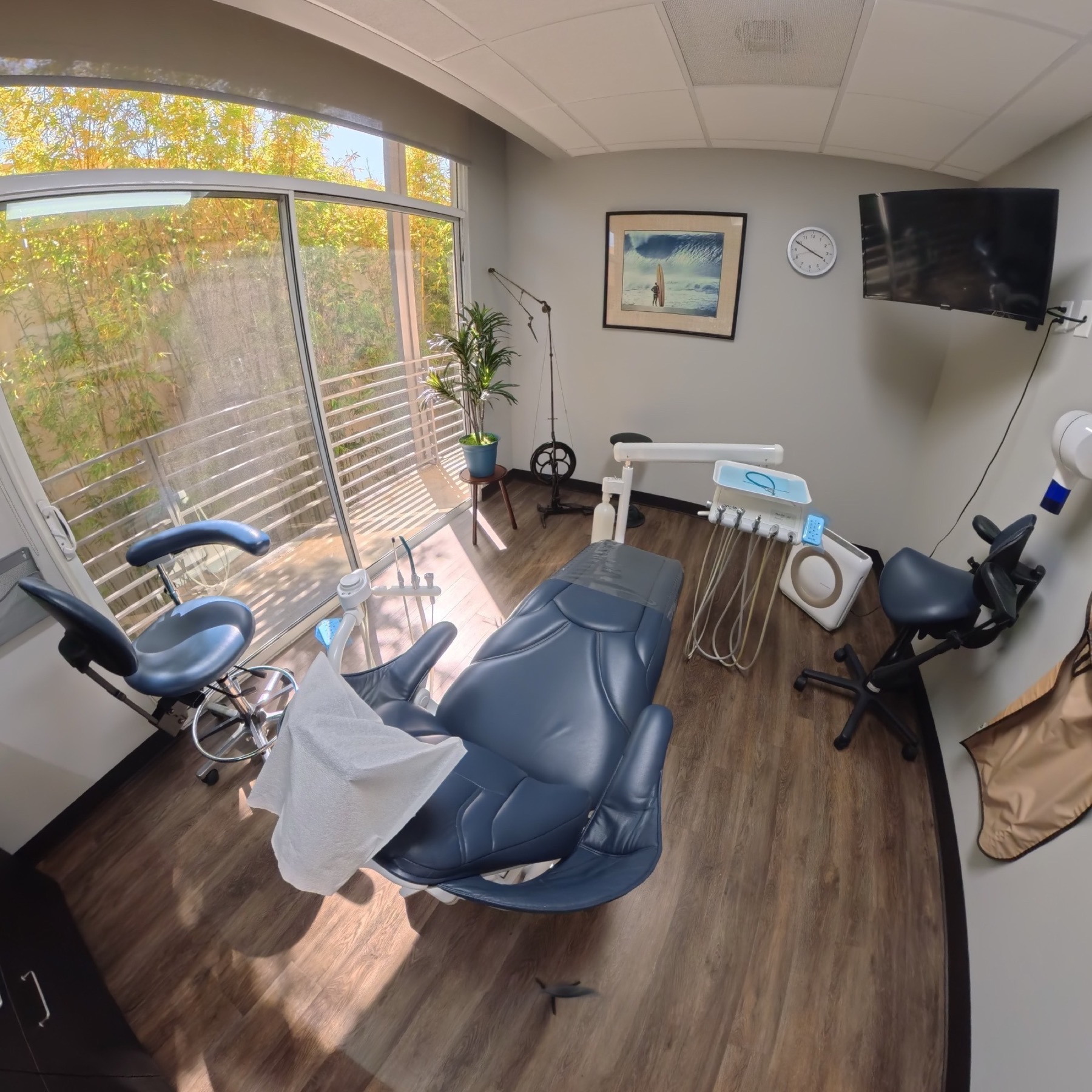 Sunlit dental treatment room with a blue patient chair